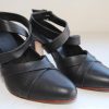 Black leather high-heeled shoes with ankle straps, stylish and elegant footwear for women, ideal for fashion-forward outfits and special occasions.