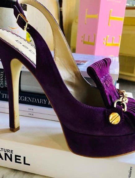Luxurious purple velvet high-heeled shoe with bow detail and gold accents, perfect for elegant fashion statements and special occasions.