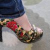 Colorful floral and animal print high heel shoe with studded embellishments, worn with cuffed jeans, perfect for fashion-forward, bold style statements.