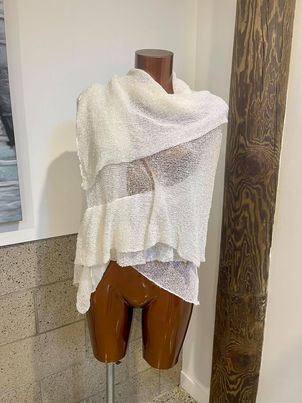 Soft beige knit shawl draped over mannequin torso, perfect for layering and cozy winter styling.