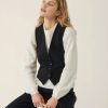 Soft cream knit sweater with eyelet detailing paired with a tailored black vest, stylish and cozy fall fashion look.
