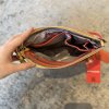 Fashionable colorful clutch purse with interior compartments, ideal for accessories and essentials, featuring a gold zipper and modern design.