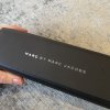 Elegant Marc by Marc Jacobs black eyewear case on textured surface, showcasing luxury designer accessories, perfect for fashion-forward style and high-end brand collection.