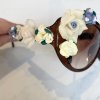 Cream-colored and blue fondant floral decorations on a glass and brown plastic decorative vase for floral art or cake toppers.