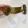Golden hammered cuff bracelet with textured honeycomb pattern, stylish jewelry accessory for women.