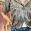 Silky satin blouse with a decorative ring detail on the collar, puffed short sleeves, paired with classic blue jeans, showcasing stylish women's fashion and elegant casual wear.