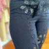 Floral embroidery on navy blue pants showcasing intricate crafted details and stylish fashion design.