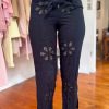 Black embroidered pants with floral cutout details and adjustable waist tie, perfect for boho-chic fashion styles and casual wear. Designed for comfort and stylish flair.