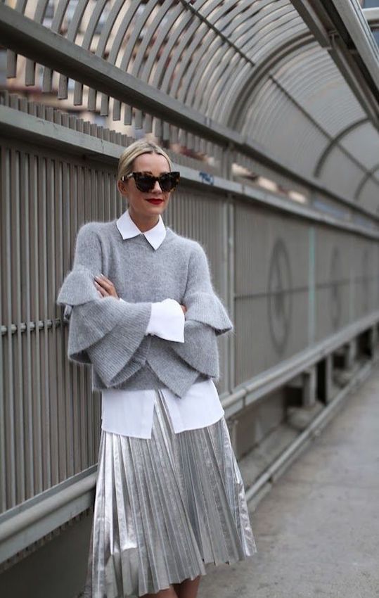 Layered gray knit sweater with bell sleeves over a white shirt and metallic pleated skirt for a chic, modern street style look. Perfect for fashionable urban outfits and stylish everyday wear.