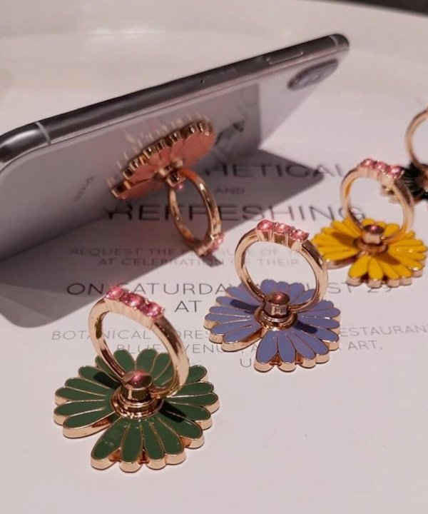 Colorful enamel floral hoop earrings displayed on a white surface with a smartphone nearby, showcasing trendy jewelry designs.