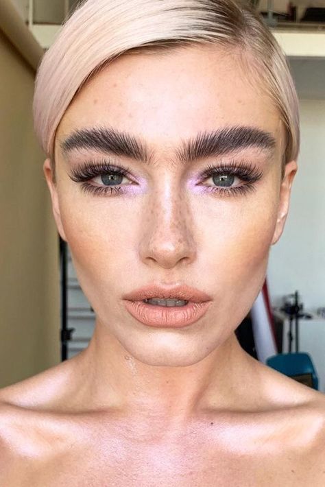 Bright blonde woman with flawless makeup, bold eyebrows, and soft nude lips, showcasing professional beauty styling and skincare.
