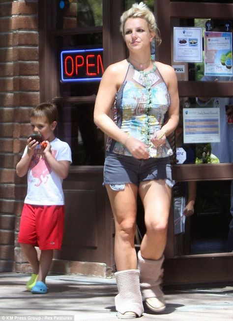 Bright woman and young boy walking past a storefront with an open sign, casual summer clothing, vibrant outdoor scene, and a relaxed atmosphere.