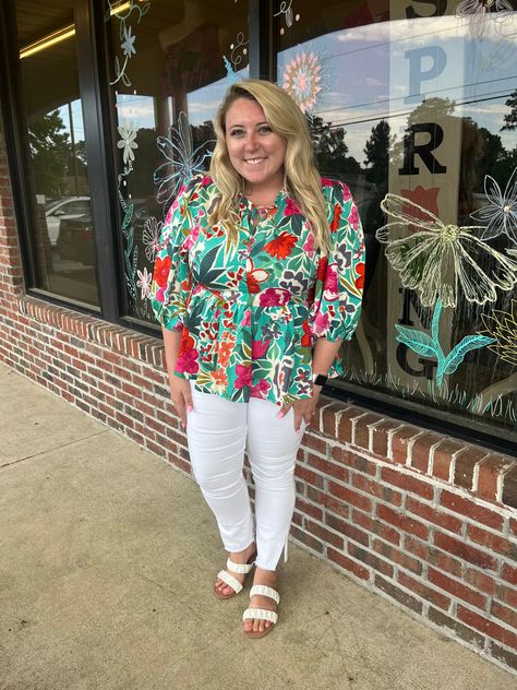 Vibrant floral blouse with colorful patterns paired with white pants, street style, and casual summer fashion for women.