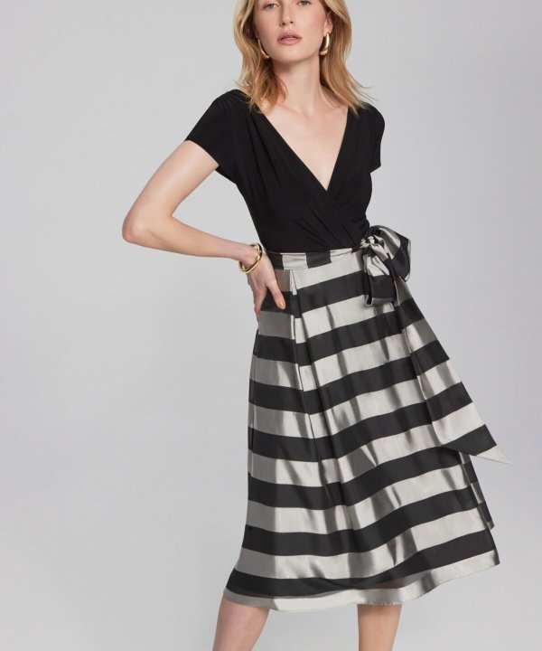 Black V-neck top paired with a high-waisted black and white striped midi skirt featuring a bow tie detail, stylish and contemporary fashion ensemble.