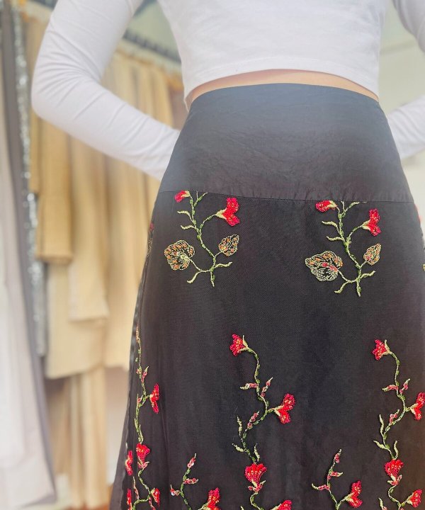 Vibrant black skirt with intricate embroidered red, green, and beige floral pattern, perfect for stylish occasions, showcasing designer craftsmanship and embroidered detailing at Katyamaker.com.