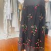 Beaded black embroidered midi skirt with red floral design, high waist, elegant boho style, perfect for summer, fall, or winter fashion accessorized with high heels.