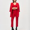 Professional woman in red business suit with blazer, pants, and high-heeled boots for fashion and business style, standing confidently against a white background, showcasing elegant and powerful corporate attire.