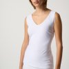 Soft white sleeveless V-neck top worn by a young woman with short red hair, showcasing minimalist fashion and comfortable summer style.