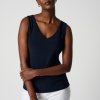 Elegant woman in a navy sleeveless top and white pants, minimalist fashion style, studio shot, modern clothing, confident pose, website fashion photography.