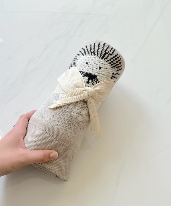 Hand-knit sock with a lion face design and a beige ribbon bow, showcasing unique and cozy handmade footwear.