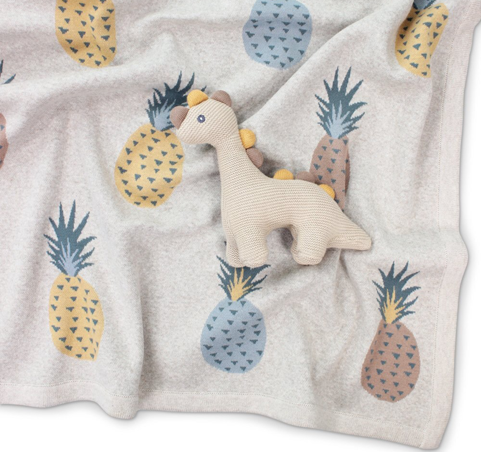 Soft pastel-colored baby blanket featuring a cute plush giraffe toy and pineapple print for nursery decor and baby gift ideas.