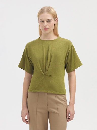 Soft green short-sleeve knit top styled with beige trousers, minimalist fashion, casual chic, spring/summer look, simple elegance, comfortable women's clothing, modern wardrobe essential.