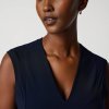 Sleek navy sleeveless dress on confident model with short hair and hoop earrings, fashion photography, modern style, elegant outfit, minimalistic background, high-quality image, professional fashion shot.