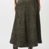 A-line wide-leg skirt with a textured tropical leaf pattern in olive green, paired with high-heeled boots, styled for fashion-forward women.
