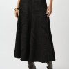 Elegant black textured midi skirt with a subtle leaf pattern, paired with knee-high heeled boots for a chic and sophisticated look, perfect for fashion-forward outfits and stylish occasions.