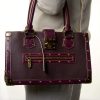Vibrant purple designer handbag with gold hardware, stud details, and structured silhouette, perfect for luxury fashion statements.