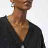 Elegant woman wearing a black speckled cardigan, showcasing stylish jewelry and modern fashion accessories, perfect for fashion-forward looks and everyday wear.