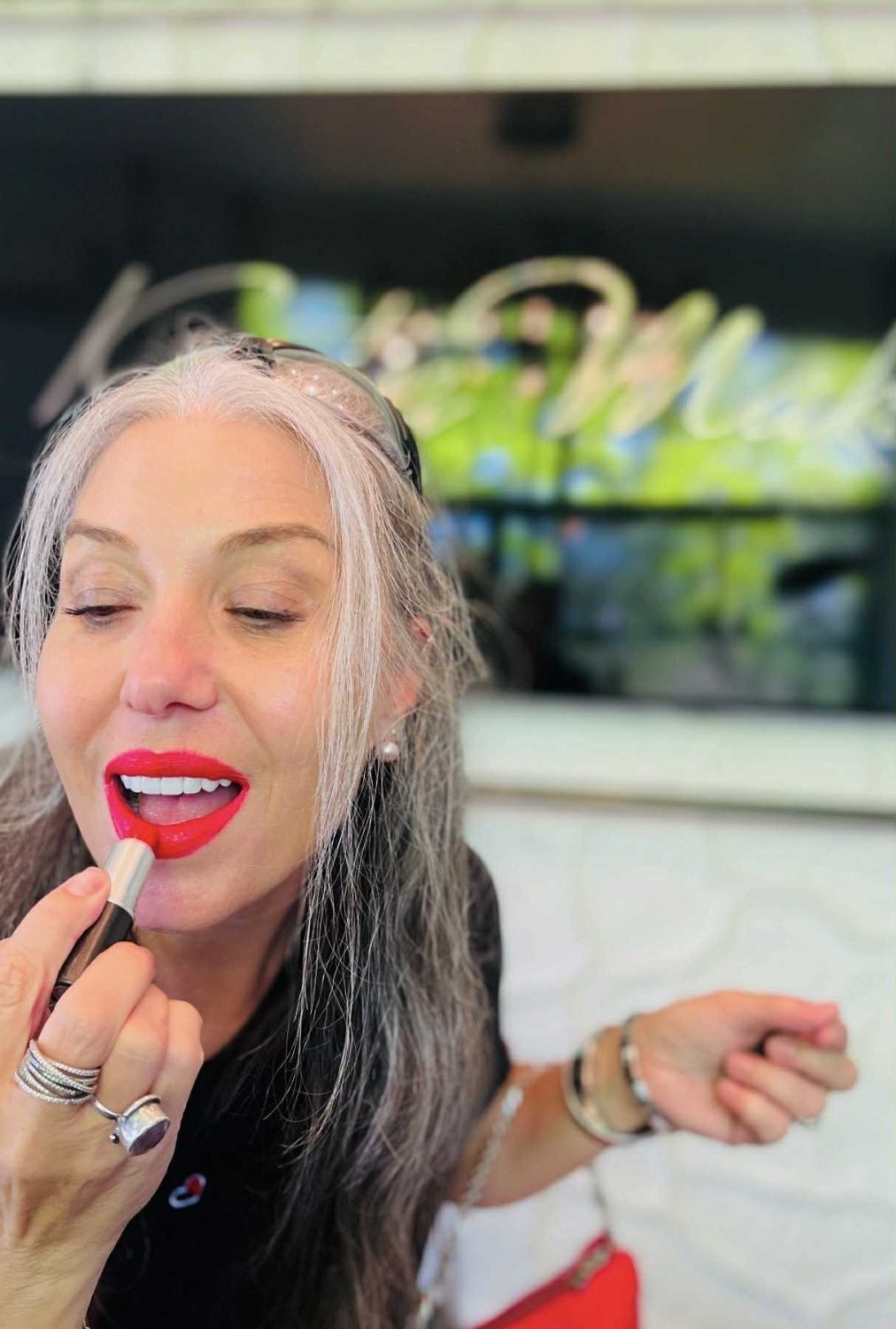 1. Senior woman applying bright red lipstick, showcasing makeup artistry and beauty tips.